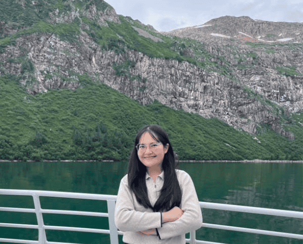 Woman Smiling On Boat With Mountain Lake